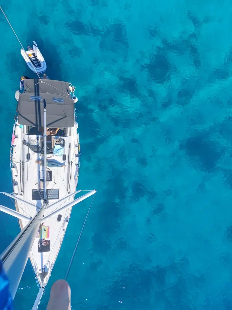 Blick vom Mast senkrecht nach unten auf das Deck und türkises Wasser