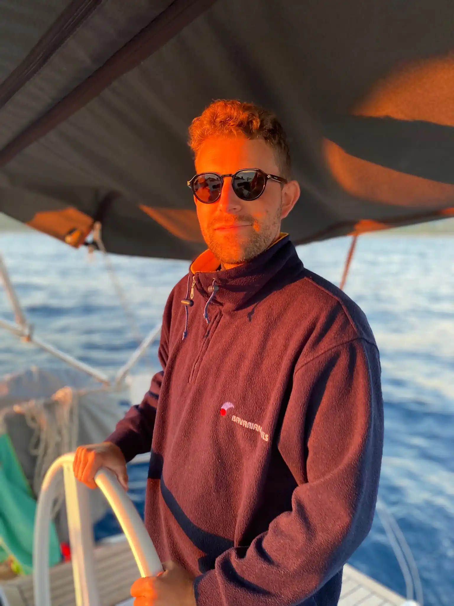 Moritz am Steuer einer Segelyacht im warmen Licht des Sonnenuntergangs