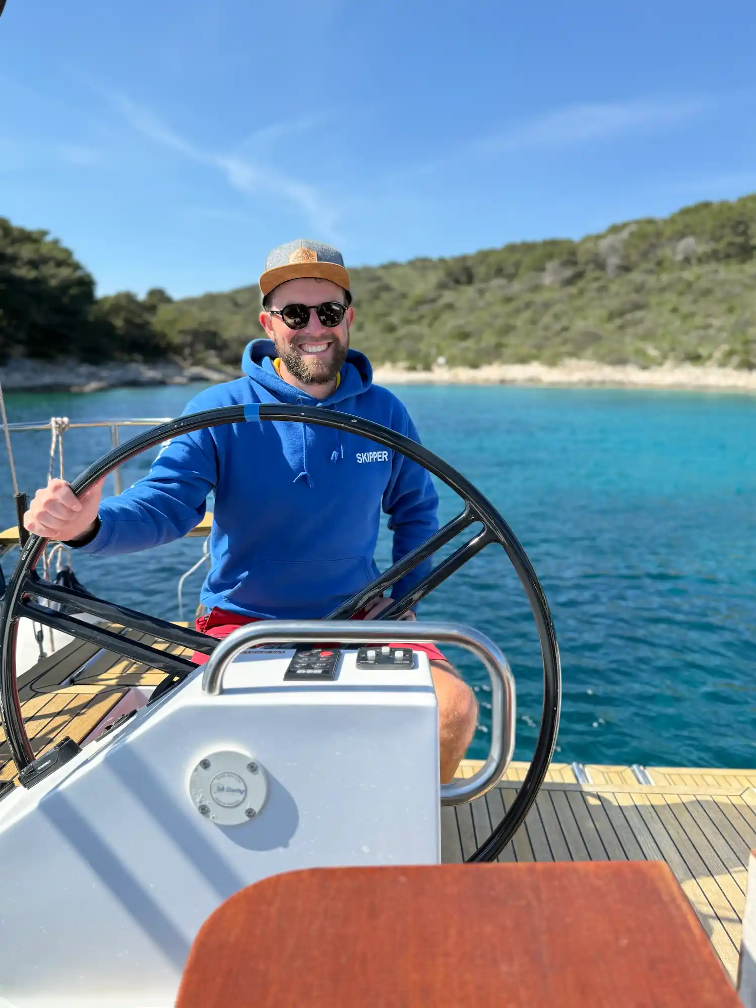 Moritz am Steuer einer Segelyacht in einer ruhigen Bucht
